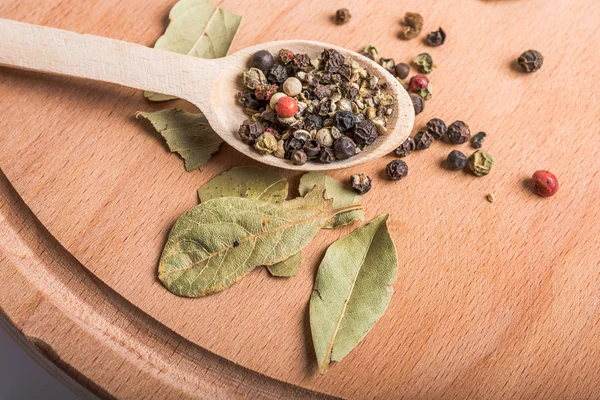 Spoon with spices and  bay leaves on wooden board — Stock Photo, Image