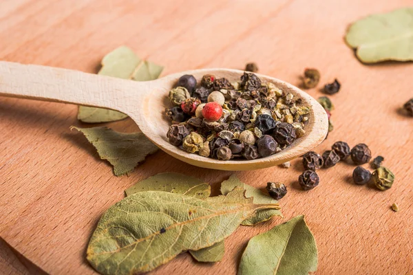 Wood spoon with spices and  bay leaves on wooden board — Stock Photo, Image