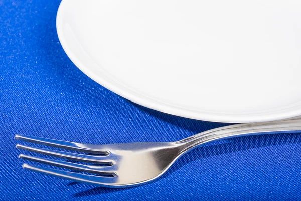 Tenedor y plato sobre fondo azul —  Fotos de Stock