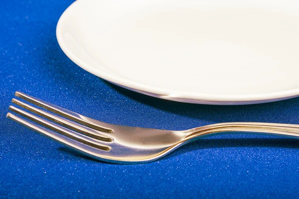 Tenedor y plato sobre fondo azul — Foto de Stock
