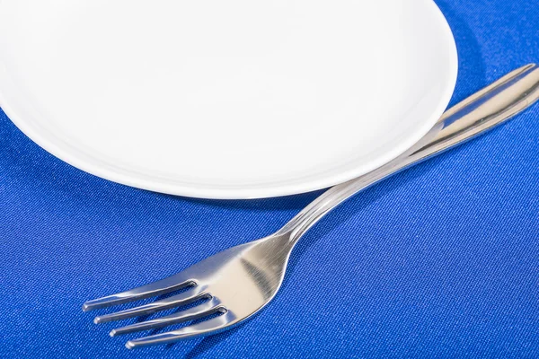 Tenedor y plato sobre mantel azul —  Fotos de Stock