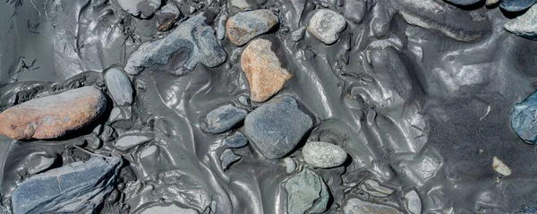 Błoto, muł rzeczny i skały pozostawione nad rzeką do wykorzystania jako tło tekstury. — Zdjęcie stockowe