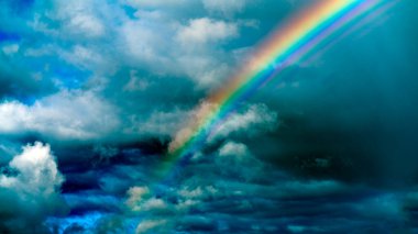 Bulutlu gökyüzünün arka planında yağmurdan sonra gökkuşağı.