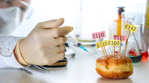 A lab technician injects a donut decorated with supplement labels E.