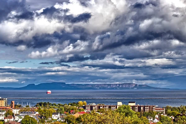 Cloudy drama in grey over the Sleeping giant with the lone grain ship - Thunder Bay, ON, Canada