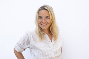 Sarı kotlu ve mavi gözlü sarışın kadın beyaz arka planda poz veriyor ve mutlu.