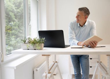 Mavi gömlekli iş adamı ayakta duruyor ve tabletiyle çalışıyor.