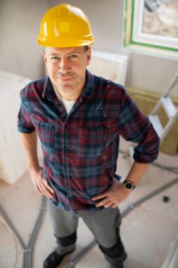 İnşaat işçisi portresi inşaat alanında sarı kaskla bir iç oda veya çatı katında. 