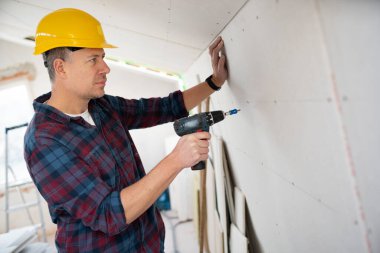 drywall worker with yellow safety helmet works on building site in a house clipart