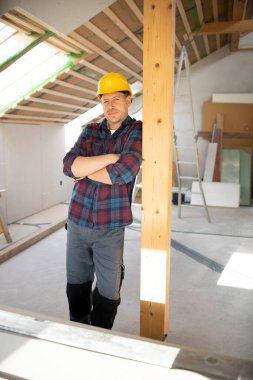 Sarı kasklı alçıpan işçisi inşaat alanında çalışıyor.