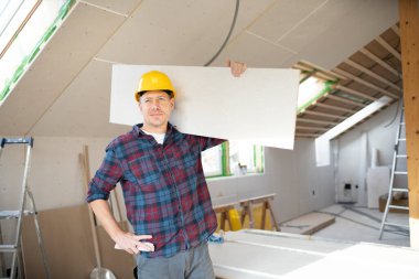 Sarı kasklı alçıpan işçisi inşaat alanında çalışıyor.