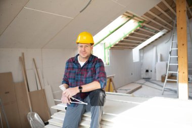 İnşaat alanındaki sarı kasklı adam alçıpan inşaatında çalışıyor.