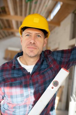 İnşaat işçisi portresi inşaat alanında sarı kaskla bir iç oda veya çatı katında. 