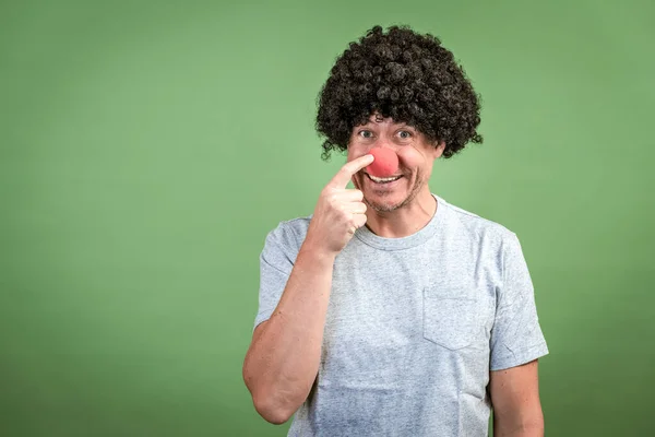 Człowiek Czarną Peruką Czerwonym Nosem Klauna Pozowanie Przed Zielonym Tle — Zdjęcie stockowe