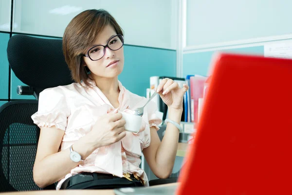 Una donna in ufficio per un computer portatile con una tazza di caffè — Foto Stock