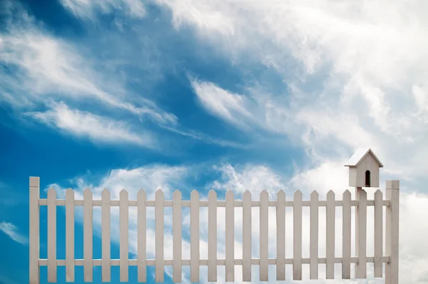 White fence with bird house and blue sky — Stock Photo, Image