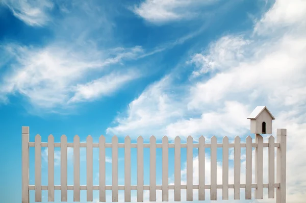 Vitt staket med fågel hus och blå himmel — Stockfoto