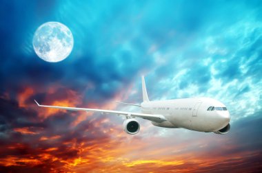 ışıklı bir moon ile gece vakti gökyüzünün yüksek uçan bir uçak