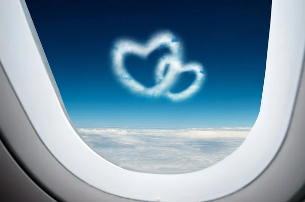 Through the aircraft windows, two heart shaped clouds in the blue sky — Stock Photo, Image