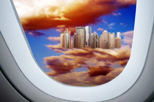 Through the aircraft windows, Higher than the clouds of skyscrapers, exaggerated performance — Stock Photo, Image