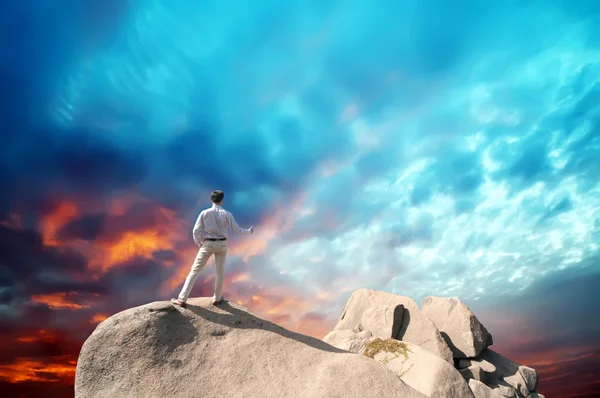 Young man standing on cliff's edge and looking into a wide valley — Stock Photo, Image