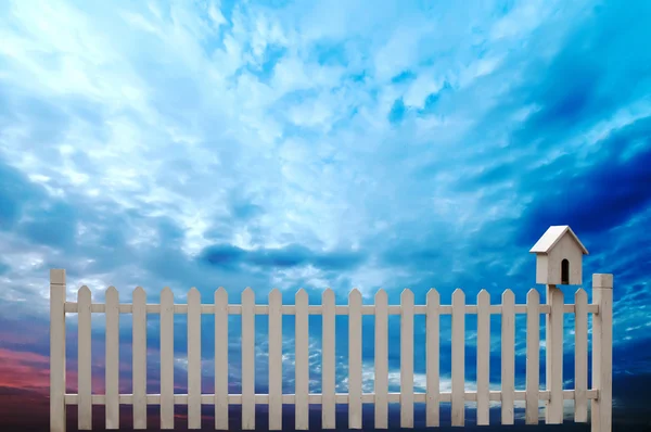 Kuş evi ve mavi gökyüzü ile beyaz çit — Stok fotoğraf