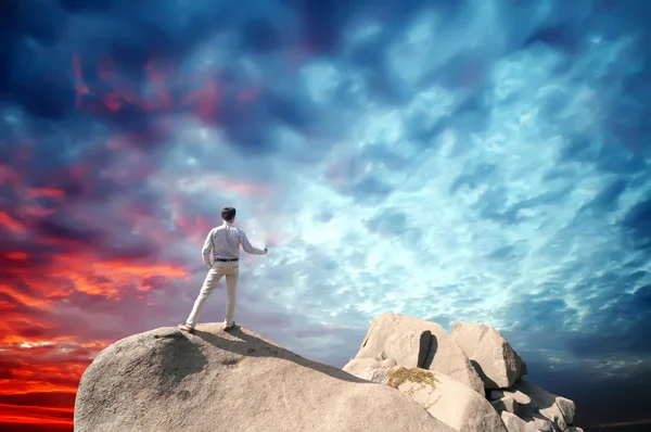 Young man standing on cliff's edge and looking into a wide valley — Stock Photo, Image