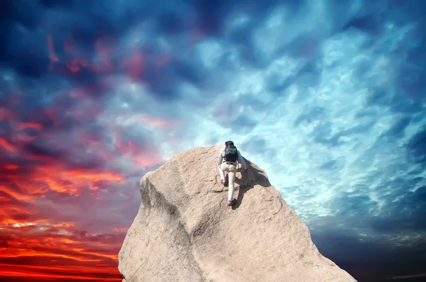 Jeune homme grimpant sur un mur de calcaire avec ciel bleu sur le fond — Photo