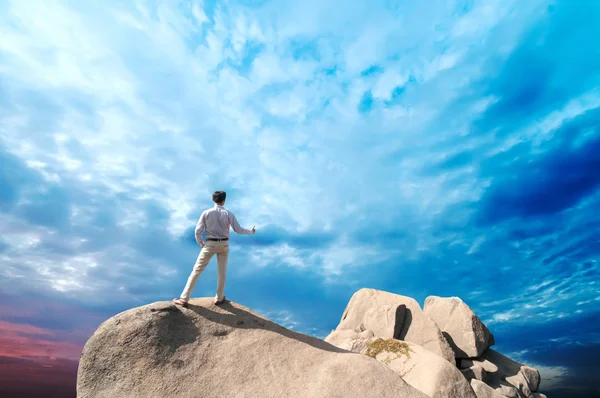 Young man standing on cliff's edge and looking into a wide valley — Stock Photo, Image