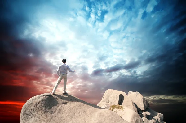 Young man standing on cliff's edge and looking into a wide valley — Stock Photo, Image