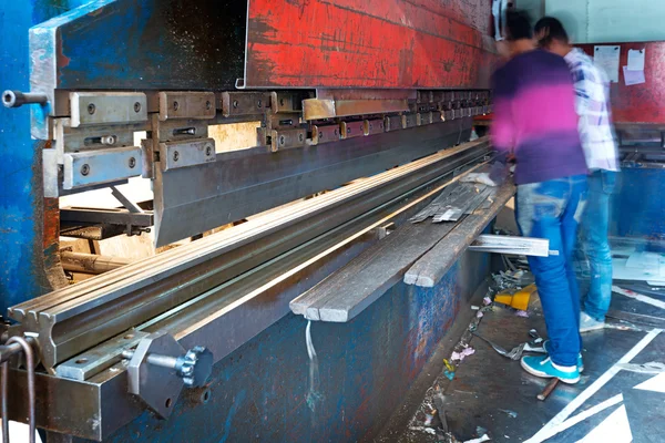 Sheet of metal and hands of worker who works on press — Stock Photo, Image