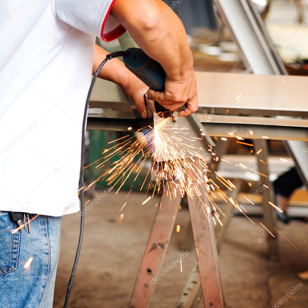 A construction worker using an angle grinder producing a lot of Stock