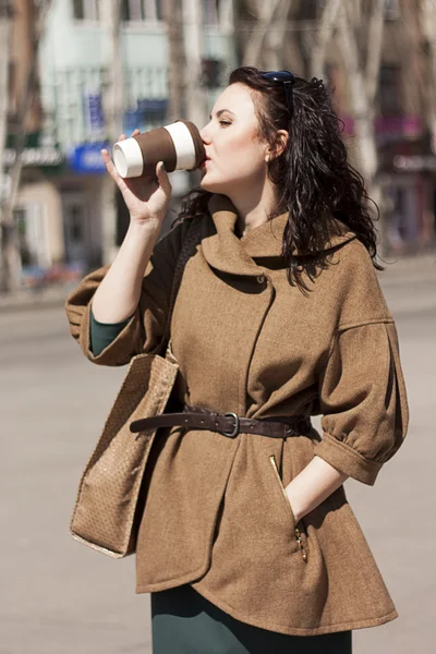 Mädchen mit einem Kaffee auf der Straße. Stockbild