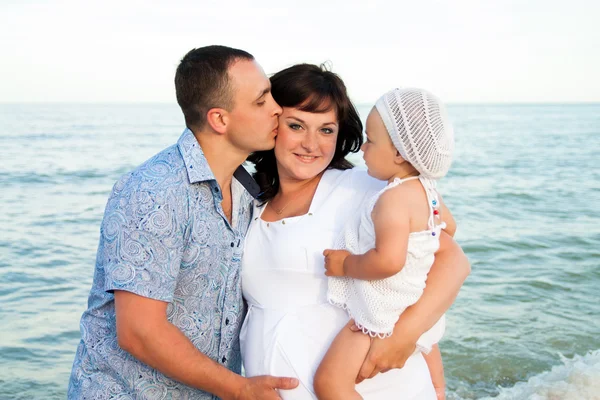 Happy pregnant family with a daughter on the beach. — Stock Photo, Image