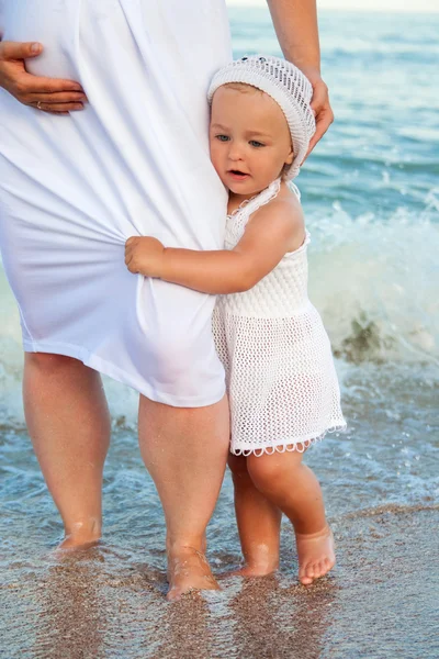 ビーチで彼女の娘と若い妊娠中の女性. — ストック写真