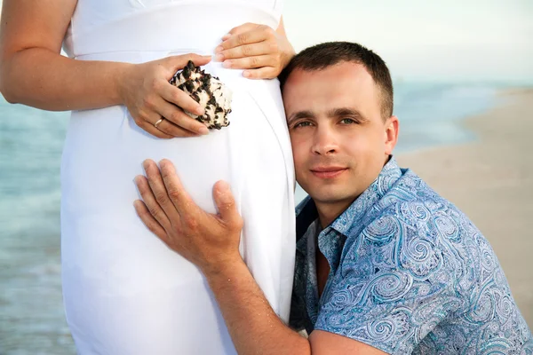 Zwangerschap. jonge liefdevol paar op het strand. — Stockfoto