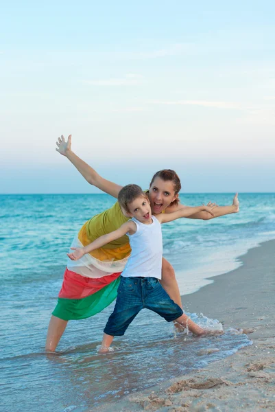 Jonge moeder met haar zoon op het avond strand. — Stockfoto