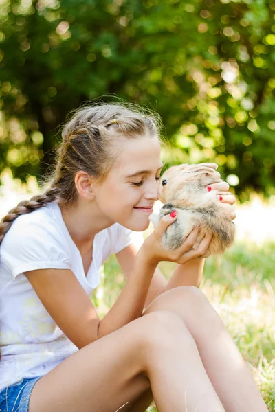 Cute little girl with a rabbit in the garden. — Stock Photo, Image