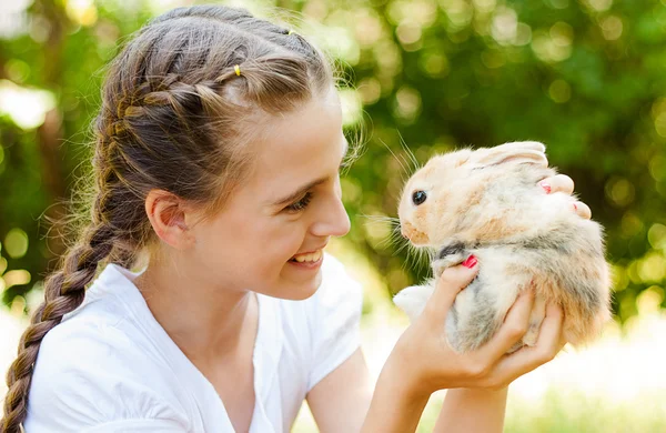 Cute little girl with a rabbit in the garden. — Stock Photo, Image