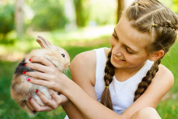 Милая маленькая девочка с кроликом в саду . — стоковое фото