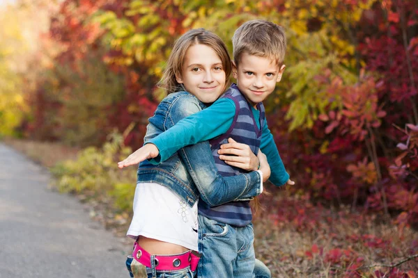 Jonge zus met broertje in het najaar park. — Stockfoto