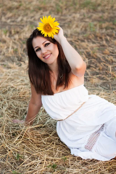 Hermosa chica con girasol en el heno . — Foto de Stock