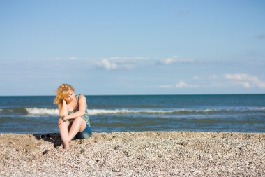 Sahilde oturan düşünceli genç bayan.