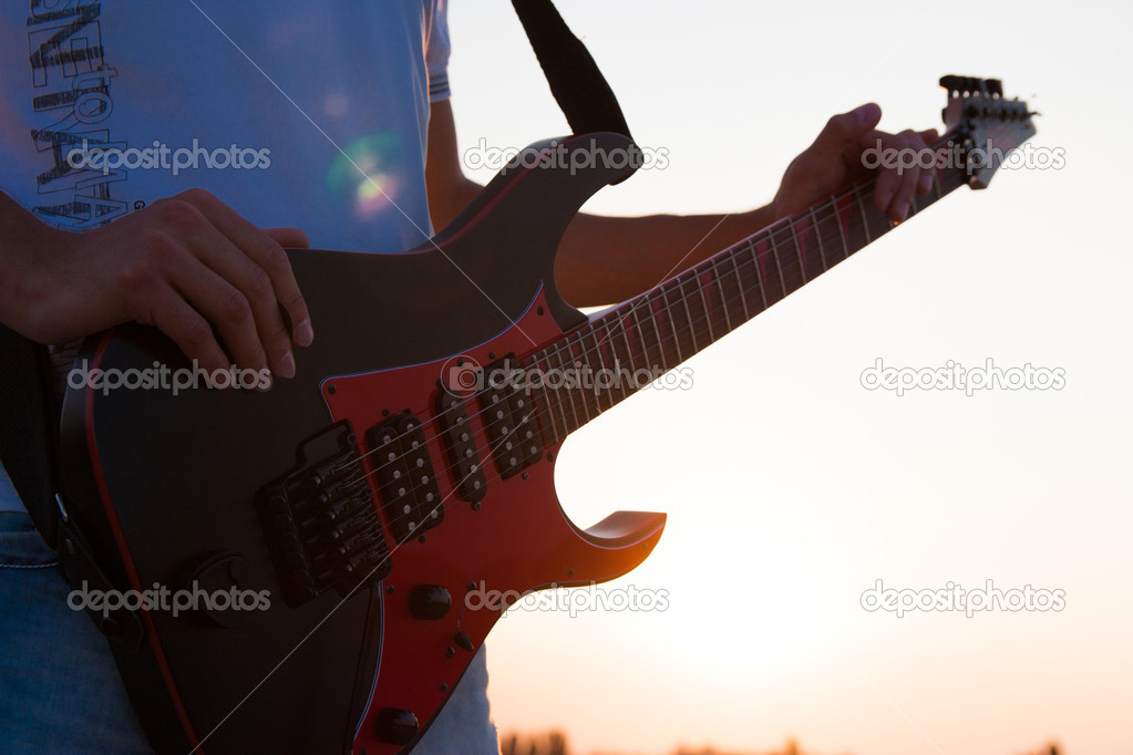 Man playing a guitar at sunset