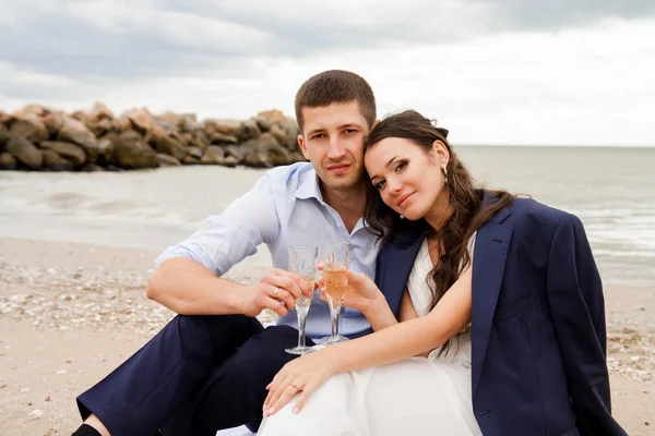 Loving bride and groom sitting on the seashore. — Stock Photo, Image