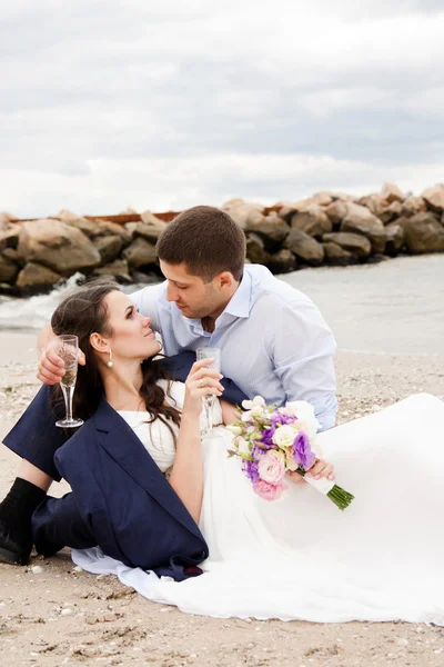 Loving bride and groom sitting on the seashore. — Stock Photo, Image