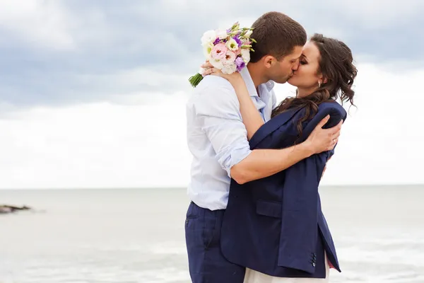 Romantic bride and groom are kissing near the sea. — Stock Photo, Image