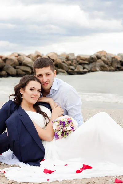 Loving bride and groom sitting on the seashore. — Stock Photo, Image