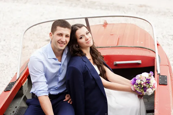 Stylish newlyweds sitting in a boat on the beach.