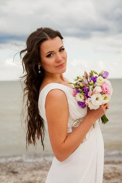 Noiva gentil com um buquê na praia . — Fotografia de Stock